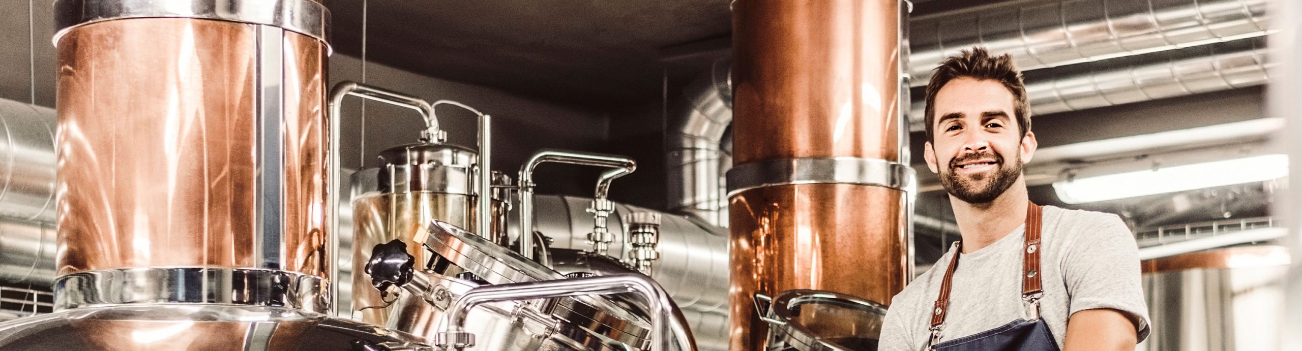 Man in front of copper tanks in a food manufacturing facility